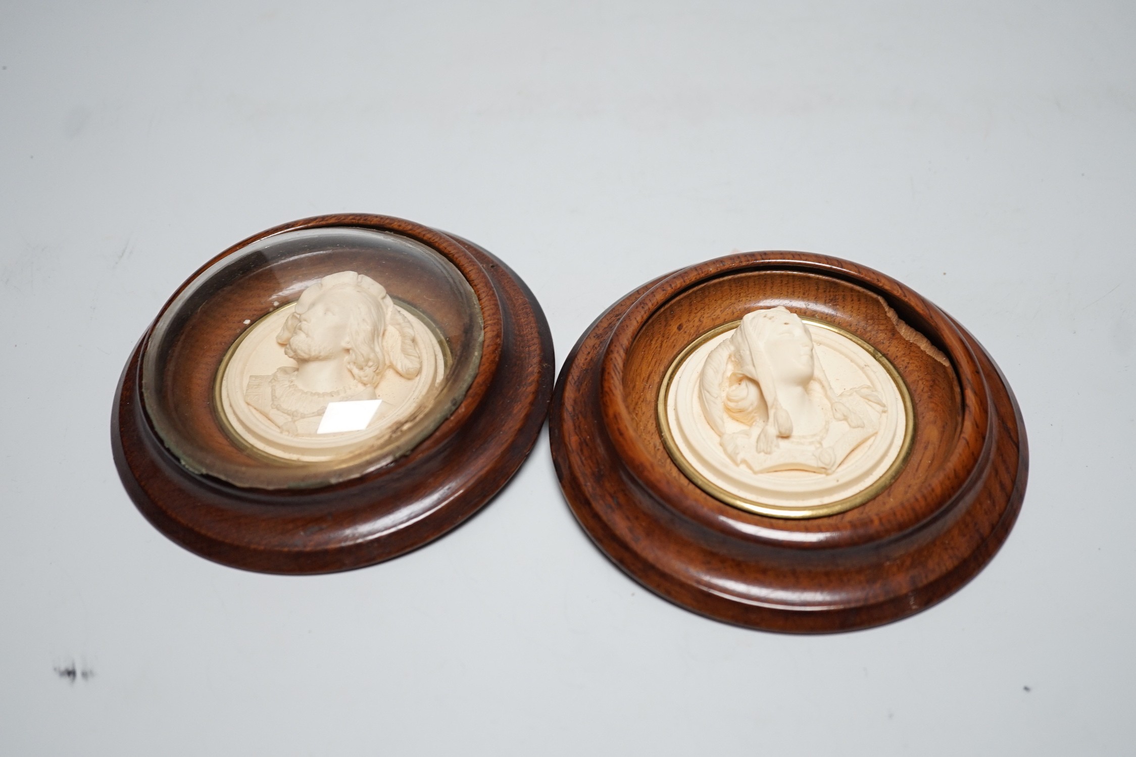 A pair of late 19th century carved and moulded composition portrait roundels, in oak frames